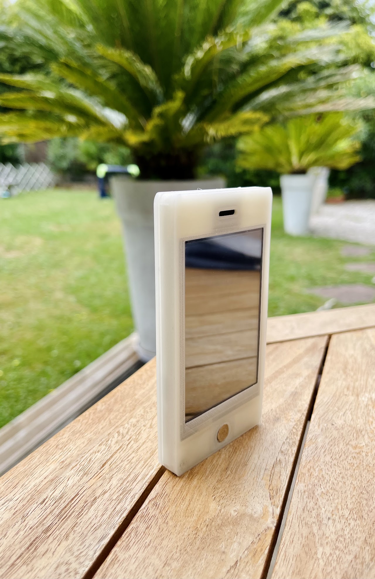 Image du téléphone de face posé verticalement sur une table en bois.